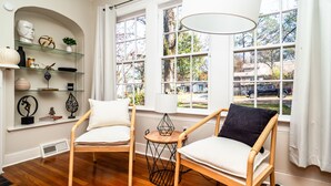 A room with two wooden chairs, a small round table, and a shelf with decorative items. - NEW! Stylish and Modern Home In the Heart of the Popular Fondren District (Jackson)
