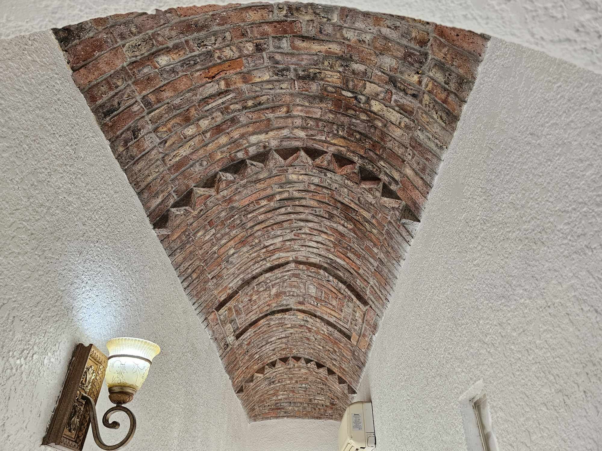 A brick archway with a light fixture at the base.
