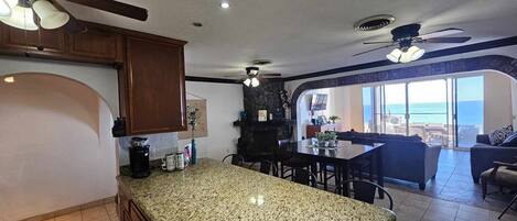 A kitchen with granite countertops, wooden cabinets, and a dining area with a view of the ocean.