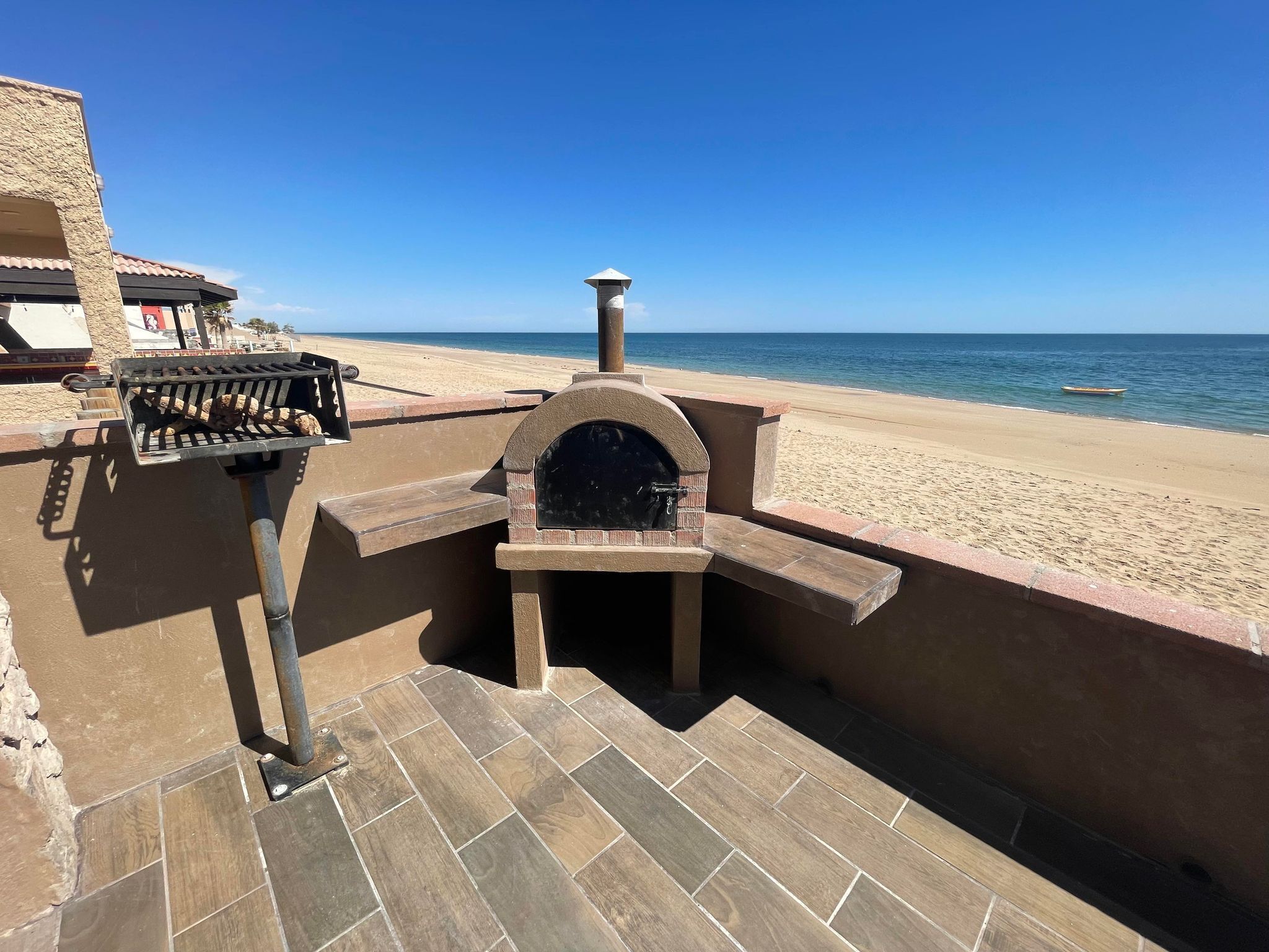 A barbecue grill and oven setup on a patio overlooking a beach.