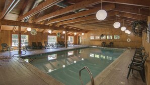 An indoor swimming pool with wooden beams, lounge chairs, and hanging lights. - Shuttle to Loon, Hot Tub & Pool! (Lincoln)