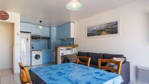A compact kitchen with a washing machine, a dining table with chairs, and a painting on the wall. - Bright apartment with terrace in Erquy | 4 guests | Ref 531 (ERQUY)