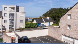 A modern building with a staircase, a parking area, and a view of the sea. - Bright apartment with terrace in Erquy | 4 guests | Ref 531 (ERQUY)