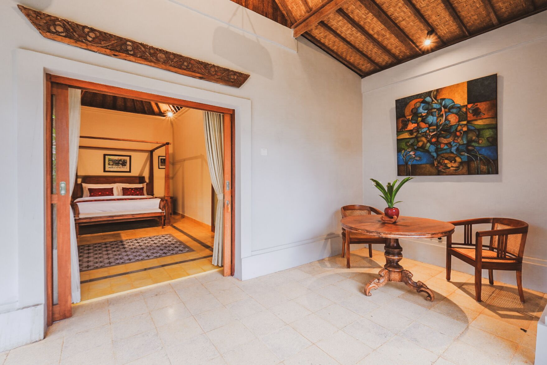 A room with a bed, a dining table with chairs, and a painting on the wall.
