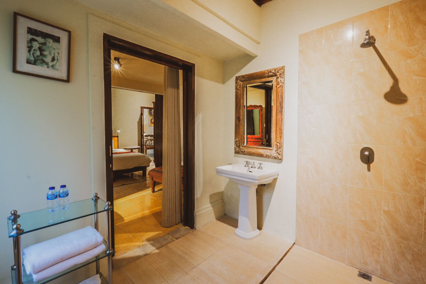 Une salle de bain avec une douche, un lavabo et une commode avec un plateau en verre, ainsi que des serviettes.