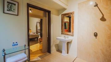 Une salle de bain avec une douche, un lavabo et une commode avec un plateau en verre, ainsi que des serviettes.