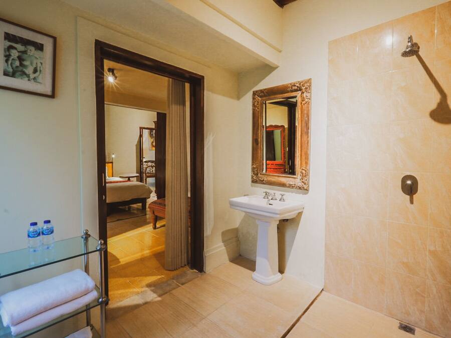 Une salle de bain avec une douche, un lavabo et une commode avec un plateau en verre, ainsi que des serviettes.
