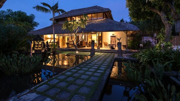 A large house with a thatched roof, a swimming pool, and lush greenery. - Bebek Cottages Sanur (Denpasar)