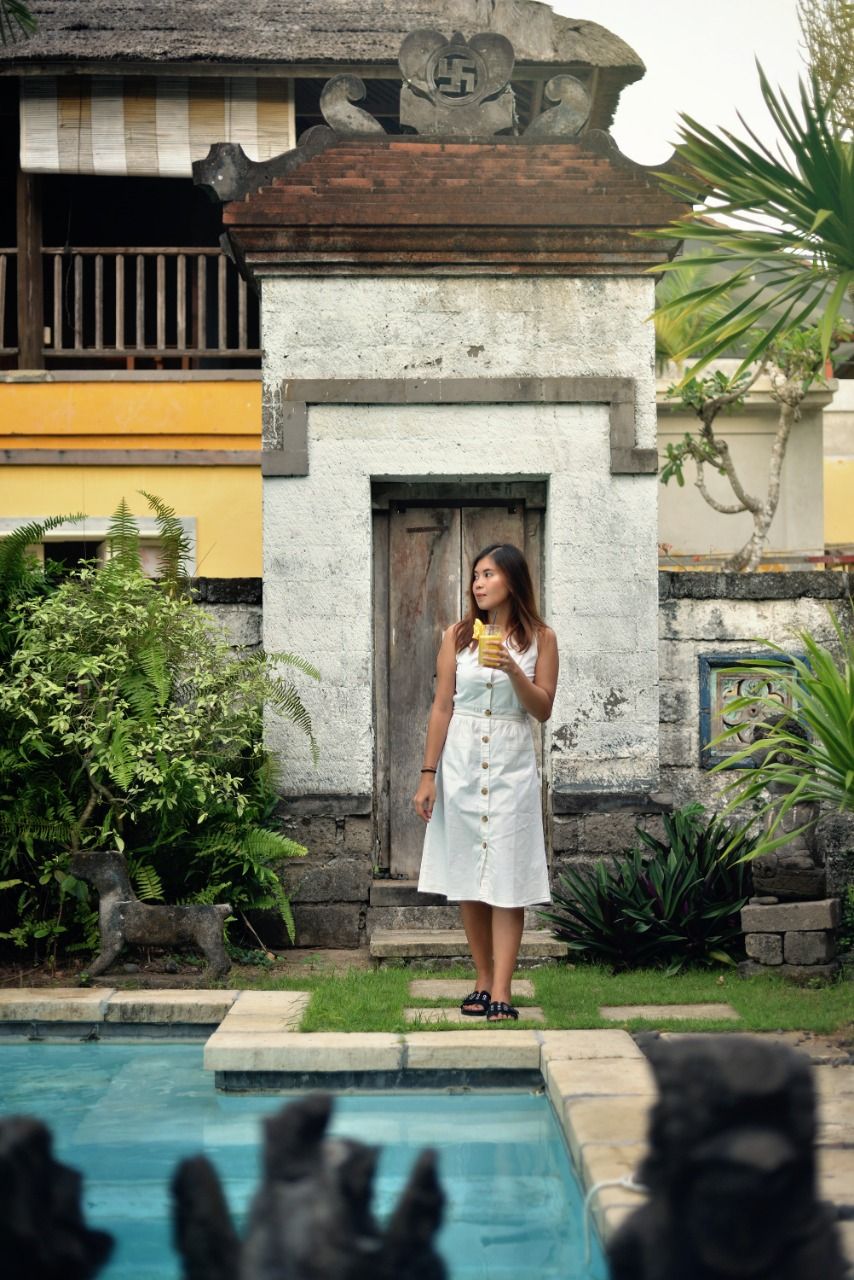 A person standing by a pool with a building in the background.