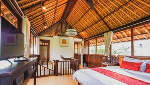A room with a bed, a desk, a chair, and a television. - Bebek Cottages Sanur (Denpasar)