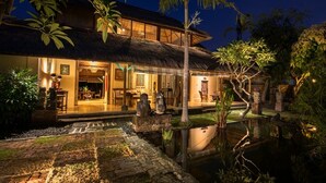 A two-story building with a thatched roof, a pool, and a garden with tropical plants. - Bebek Cottages Sanur (Denpasar)