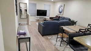 A modern living room with a sofa, a TV, and a dining area with a table and chairs. - Premium Modern TH • Near Dulles Airport • 2 Free Parking (Clifton)