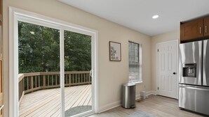 A modern kitchen with a large sliding glass door leading to a wooden deck, a stainless steel refrigerator, and a framed inspirational quote on the wall. - Premium Modern TH • Near Dulles Airport • 2 Free Parking (Clifton)