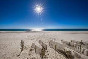 A beach with a clear sky, a bright sun, and a sandy shore. - Crystal Shores 1405 | Beach Front | Indoor Pool, Zero Entry Pool, Sauna and much more! (Gulf Shores)