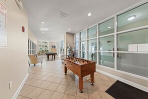A spacious indoor area with a foosball table, a pool table, and a seating area. - Crystal Shores 1405 | Beach Front | Indoor Pool, Zero Entry Pool, Sauna and much more! (Gulf Shores)
