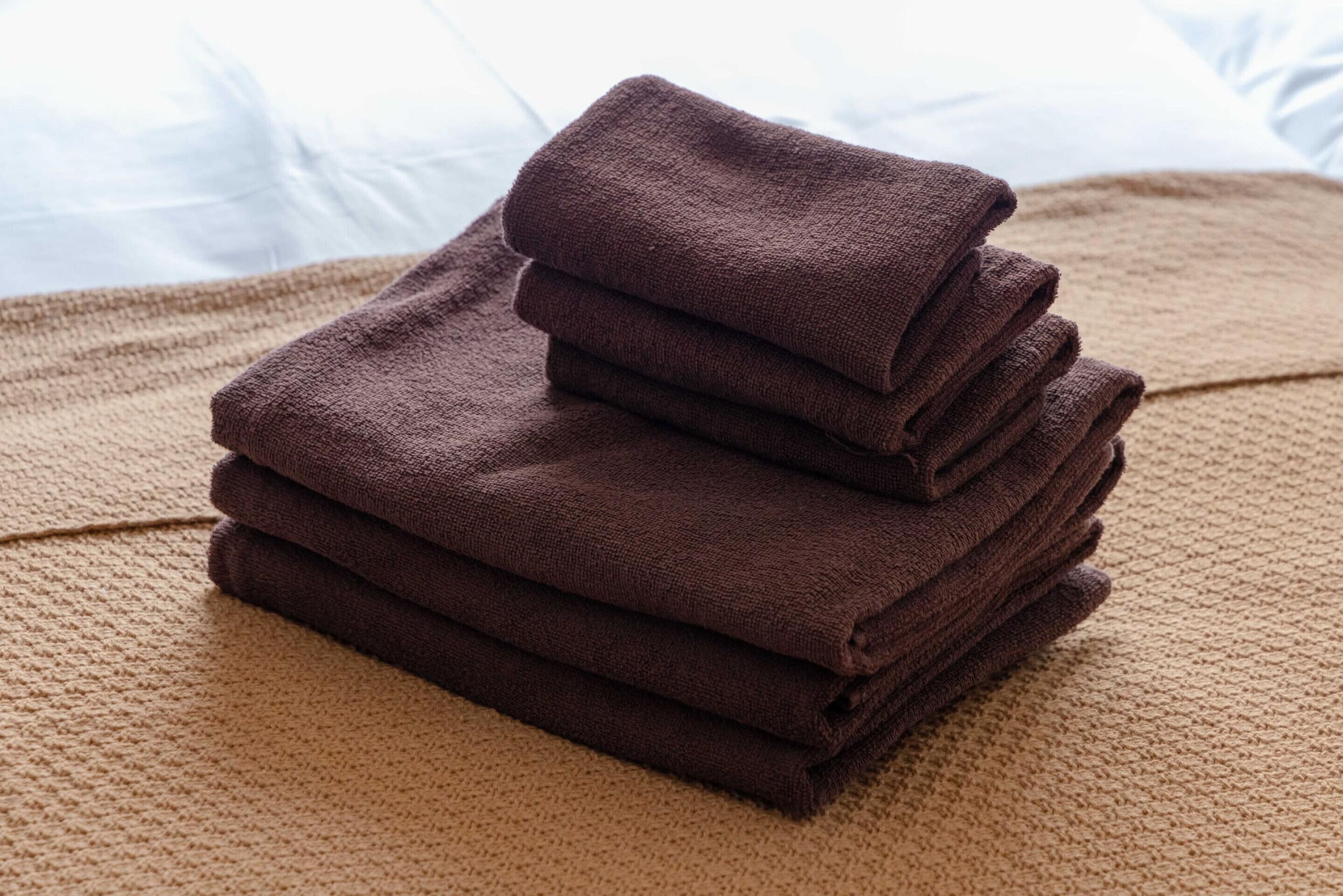 A stack of folded towels on a textured beige surface.