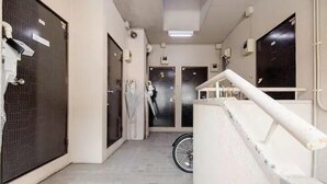 A corridor with a bicycle, a white railing, and doors with security cameras. - MAISON Shin-Nakano (Tokyo)