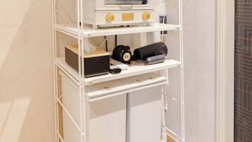 A white metal shelf unit with various kitchen appliances and storage containers.