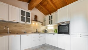 Een moderne keuken met witte kasten, een houten plafond en een betegelde vloer.