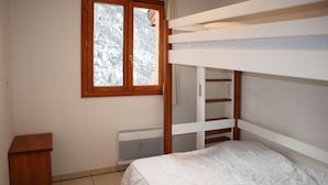 A bunk bed with a white mattress, a wooden headboard, and a window with a view of a snowy landscape. - N°609 Balcon des Airelles (LES ORRES 1800)
