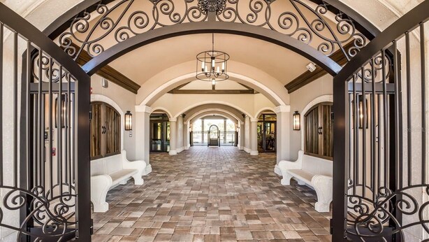 A spacious hallway with a tiled floor, white benches, and ornate black metal railings. - Resort-style 1st Floor Condo in Lakewood National Golf Community-Lakewood Ranch! (Lakewood Ranch)