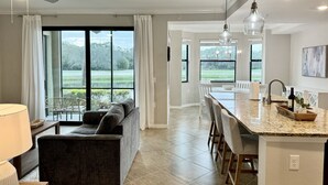 A modern kitchen with a large island, dining area, and a view of a lake. - Resort-style 1st Floor Condo in Lakewood National Golf Community-Lakewood Ranch! (Lakewood Ranch)