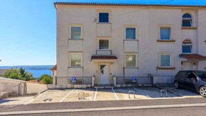 A two-story building with a flat roof, a central entrance, and a parking area with two marked spaces. - Holiday apartment with a nice balcony (Dramalj)