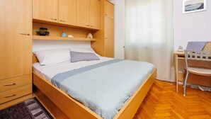 A bedroom with a wooden bed, a desk, and a chair. - Holiday apartment with a nice balcony (Dramalj)
