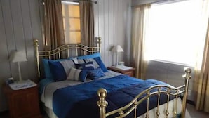 Een slaapkamer met een bed, twee nachtkastjes, een raam en gordijnen.