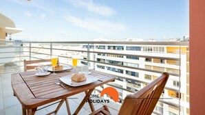Un balcón con una mesa lista para el desayuno, que incluye croissants, jugo y un vaso de zumo de naranja.