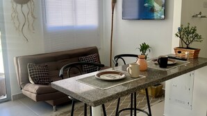 Ett modernt kök med matplats, en takfläkt, en tv och en krukväxt.