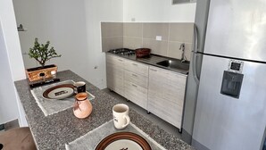 Ett modernt kök med bänkskivor i granit, ett kylskåp i rostfritt stål och en gasspis.