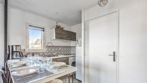 A modern kitchen with a dining area, a washing machine, and a window with a view.