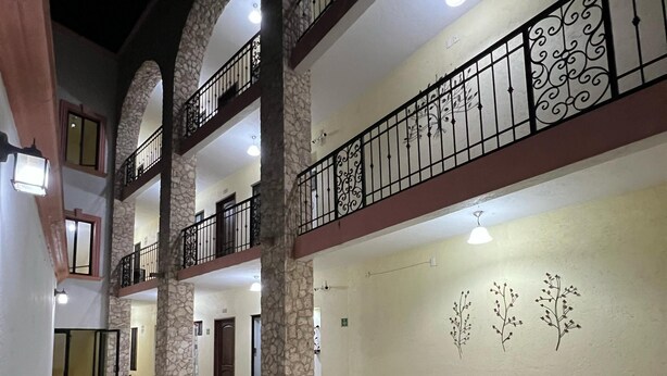 Un patio de varios niveles con pilares de piedra, mobiliario exterior y detalles decorativos en las paredes.