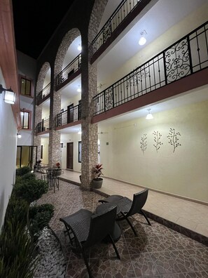 A multi-level courtyard with stone pillars, outdoor seating, and decorative wall art. - Hotel La Capilla Bernal (Ezequiel Montes)