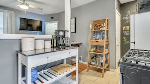Eine kleine Küche mit einer Kaffeemaschine, einem Holzbodenregal und einem Kühlschrank.