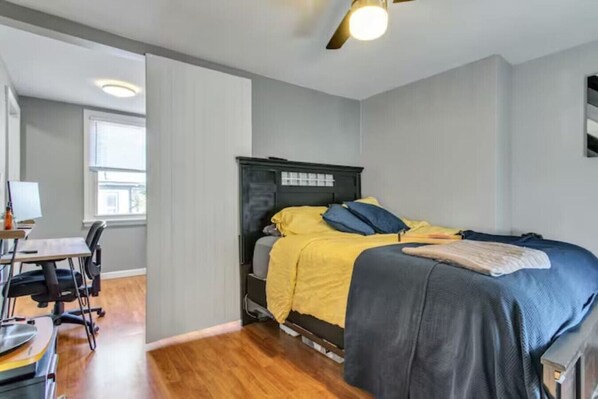 A bedroom with a bed, a desk, and a chair.