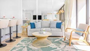 A modern living room with a sofa, chairs, a round coffee table, and a TV.