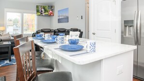 Una cocina moderna con una isla central, armarios blancos y electrodomésticos de acero inoxidable.