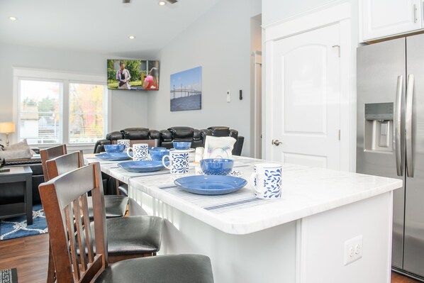 A modern kitchen with a central island, white cabinetry, and stainless steel appliances. - Bay Ridge house by Quiet Waters Park, Thomas Point Park (Annapolis)
