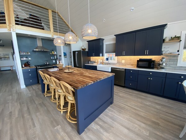 A modern kitchen with a central island, dark cabinetry, and a wooden floor. - Stunning 4 Season New Beach House - Big Traverse Bay on Lake Superior!  (Lake Linden)
