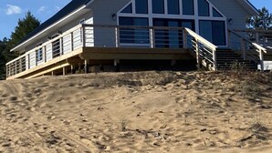 A large, modern beach house with a prominent triangular roof and large windows.