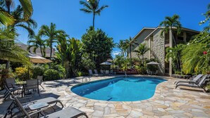 A pool area with lounge chairs and umbrellas, surrounded by palm trees and a stone deck. - 🌴AC | Garden View | 1st floor | Kalanikai #110🌴 (Kailua Kona)