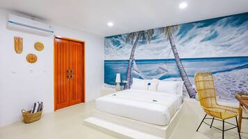 A bedroom with a bed, a chair, a hammock, and a beach mural on the wall.