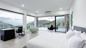 Un dormitorio moderno con una cama grande, un escritorio y vistas a un paisaje montañoso.