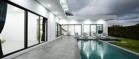 A modern house with a swimming pool, large glass doors, and a view of the countryside.