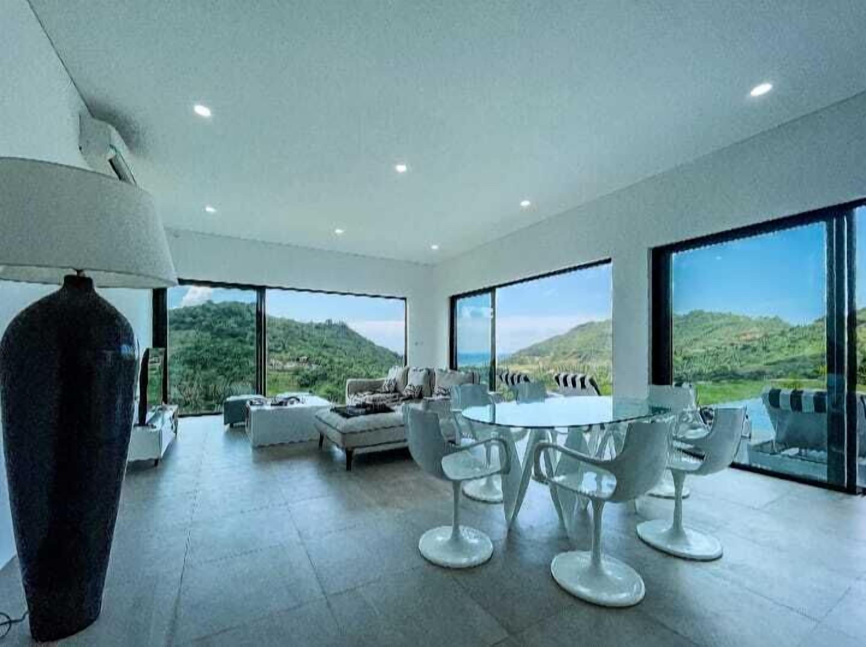 A modern interior with a dining area, seating, and large windows offering a view of the hills.