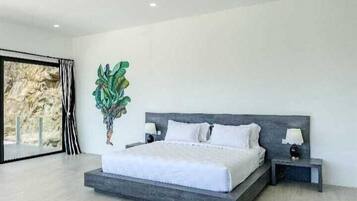 Quarto moderno com uma cama grande, mesas de cabeceira e um vaso com planta.