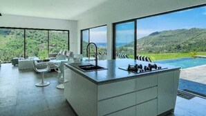 Una cocina moderna con ventanas amplias, una isla central y vistas a un paisaje exuberante.