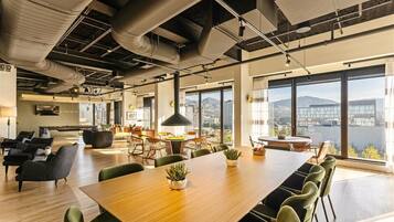 A spacious office with a large wooden table, green chairs, and potted plants.